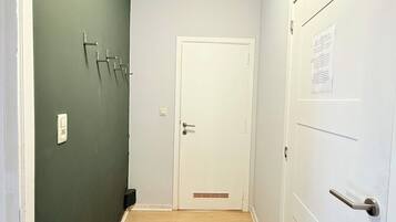 A hallway with a green wall, a white door, and a wooden floor.