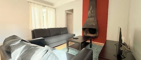 A modern living room with a black leather sofa, a small table, and a fireplace.