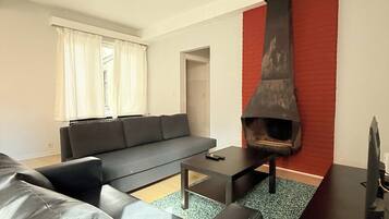 Een moderne woonkamer met een zwarte bank, een salontafel, een open haard en een tv-meubel.
