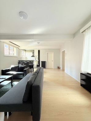 A spacious living area with a sofa, a dining table, and a kitchen in the background. - Stay in the Heart of Brussels – Steps from Grand Place & Manneken Pis (Brussels)