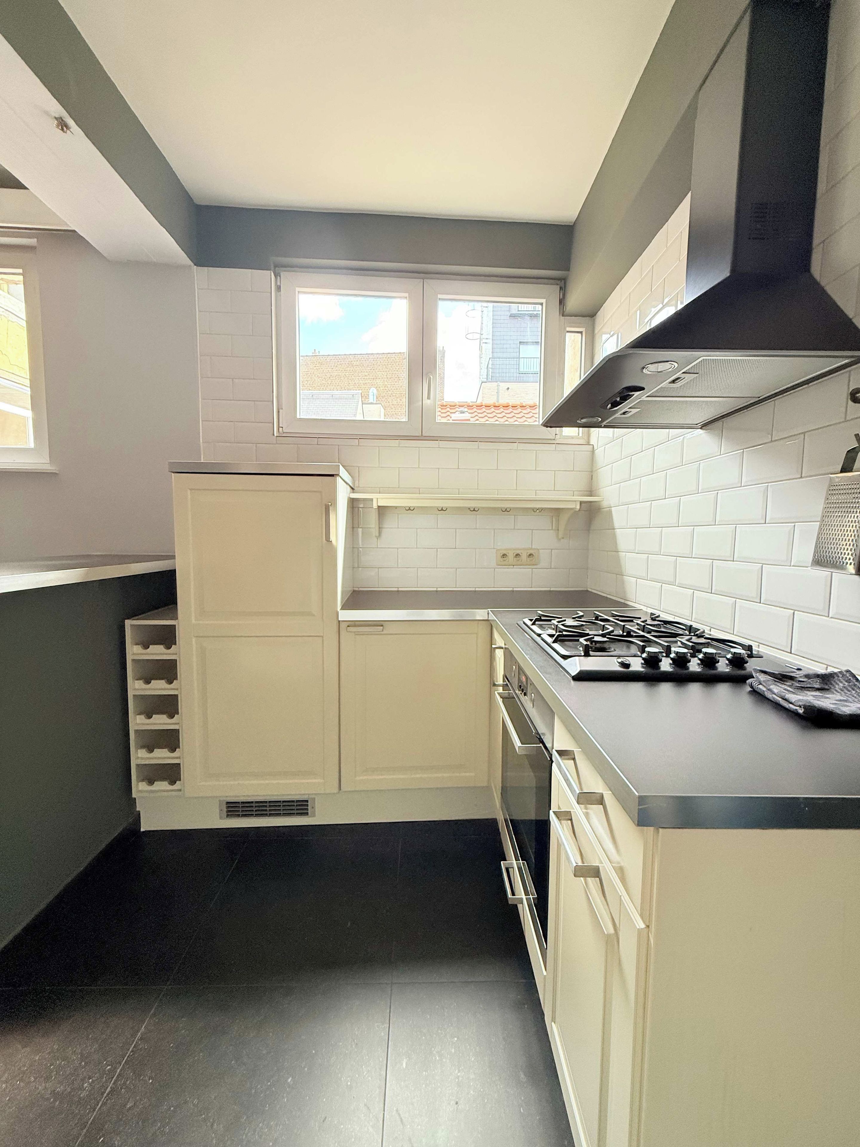 A kitchen with white cabinets, a gas stove, and a black range hood.