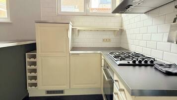 A kitchen with white cabinets, a gas stove, and a black range hood.