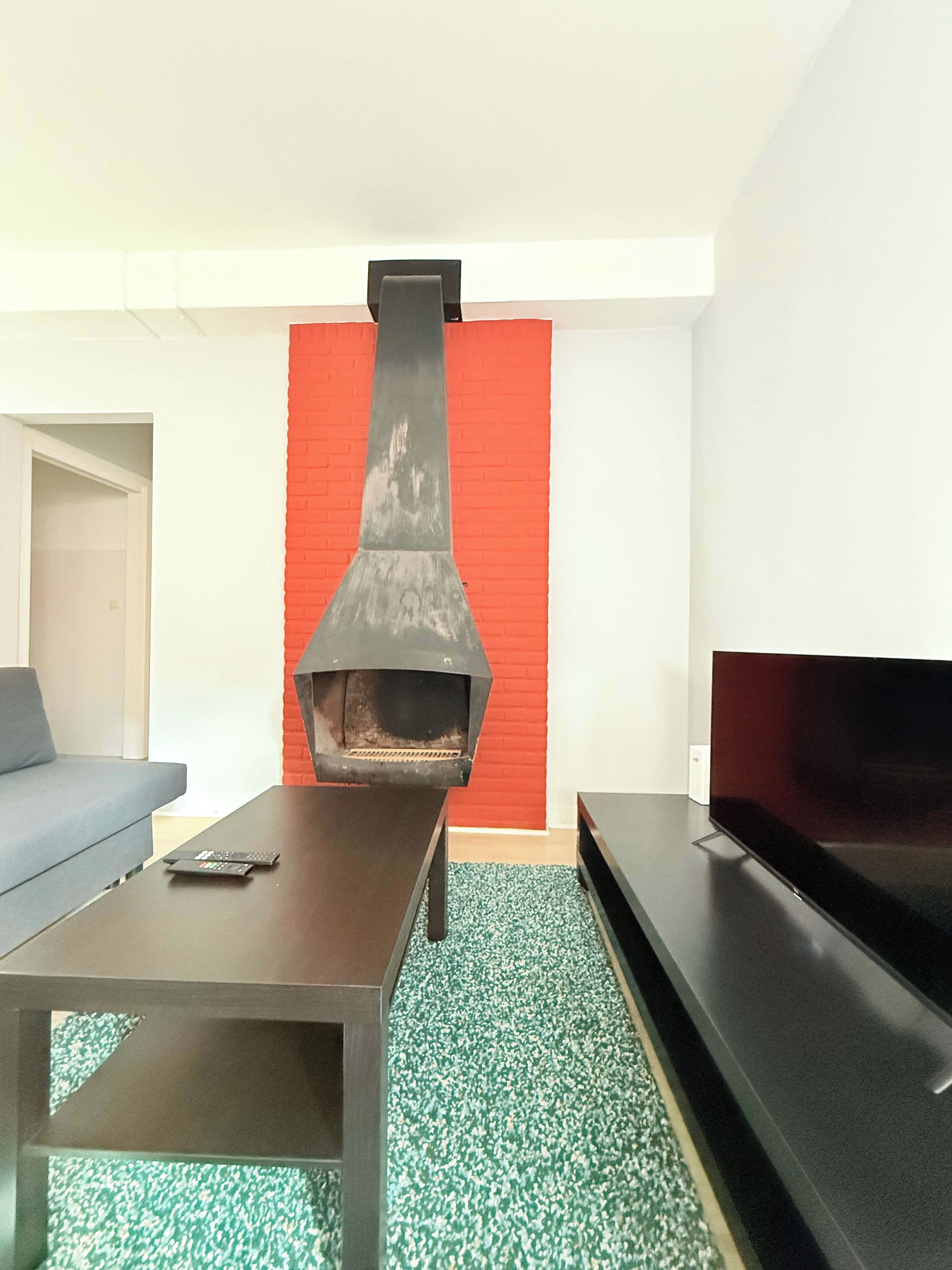 A living room with a fireplace, a sofa, a coffee table, and a flat-screen TV.