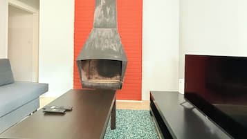 A living room with a fireplace, a sofa, a coffee table, and a flat-screen TV.