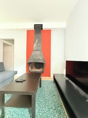 A living room with a fireplace, a sofa, a coffee table, and a flat-screen TV. - Stay in the Heart of Brussels – Steps from Grand Place & Manneken Pis (Brussels)