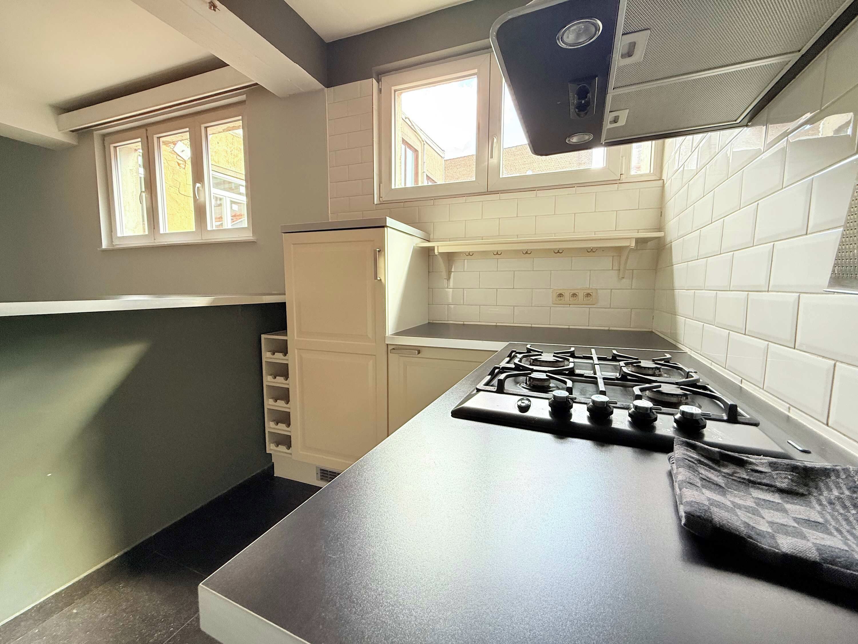A kitchen with a gas stove, a refrigerator, and a window.