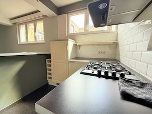 Une cuisine équipée d’une cuisinière à gaz, d’un réfrigérateur et d’une fenêtre.