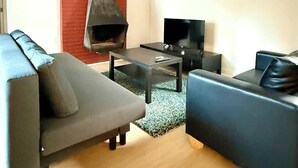 A modern living room with a fireplace, a sofa, a coffee table, and a TV.