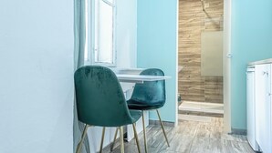 A room with a white desk, two teal chairs, a window with a checkered curtain, and a wooden wall. - Shopping Paradise 9BR For 22 People (Vienna)