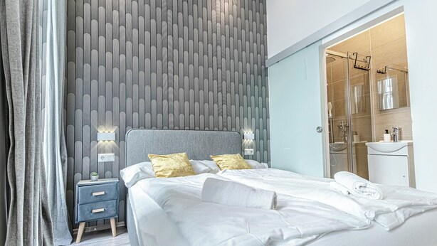 A modern bedroom with a large bed, bedside lamps, and a nightstand. - Shopping Paradise 9BR For 22 People (Vienna)