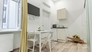 A compact kitchen with white cabinets, a microwave, and a small dining area with a table and chairs. - Shopping Paradise 9BR For 22 People (Vienna)