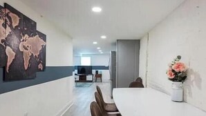 A modern dining area with a white table and chairs, a world map artwork on the wall, and a vase with flowers. - Charming townhome ground floor/basement unit (Washington)