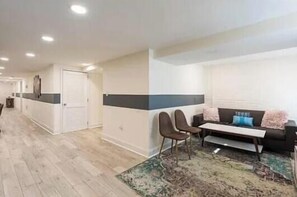 A modern living room with a sofa, chairs, a coffee table, and a patterned rug. - Charming townhome ground floor/basement unit (Washington)