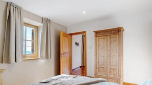 A bedroom with a bed, a wardrobe, a window with curtains, and a door leading to another room. - Apartment 'Panorama Val Di Non' with Mountain View, Wi-Fi, and Air Conditioning (Unsere Liebe Frau im Walde-St. Felix)