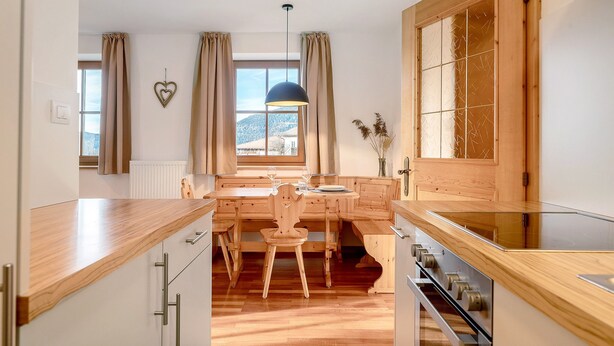 A modern kitchen with wooden cabinetry, a dining table, and a view of the outdoors. - Apartment 'Panorama Val Di Non' with Mountain View, Wi-Fi, and Air Conditioning (Unsere Liebe Frau im Walde-St. Felix)