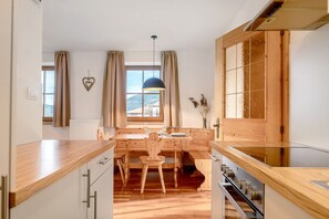 A modern kitchen with wooden cabinetry, a dining table, and a view of the outdoors. - Apartment 'Panorama Val Di Non' with Mountain View, Wi-Fi, and Air Conditioning (Unsere Liebe Frau im Walde-St. Felix)