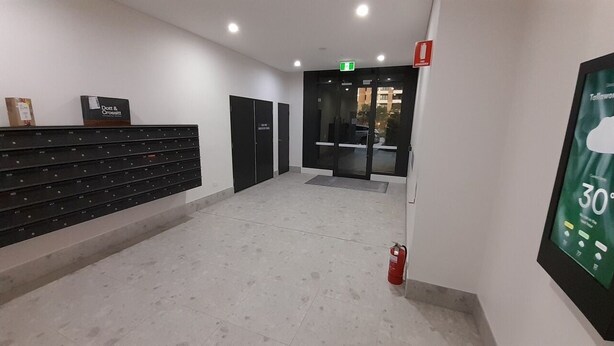 A hallway with a fire extinguisher, a sign for Don & Crossett, and a digital screen displaying the temperature.