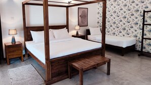 Una cama con dosel y estructura de madera, dos mesitas de noche y un banco.