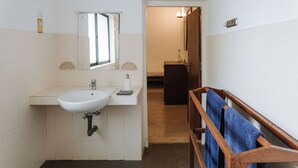 Un baño con un lavamanos blanco, un espejo y un banco de madera con toallas.