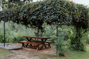 A wooden picnic table under a vine-covered pergola in a garden. - The 6th Milepost Tea Bungalow Bandarawela (Mirahawatta)