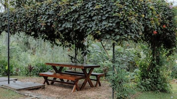 Una mesa de picnic de madera bajo una pérgola cubierta de hiedra en un jardín.
