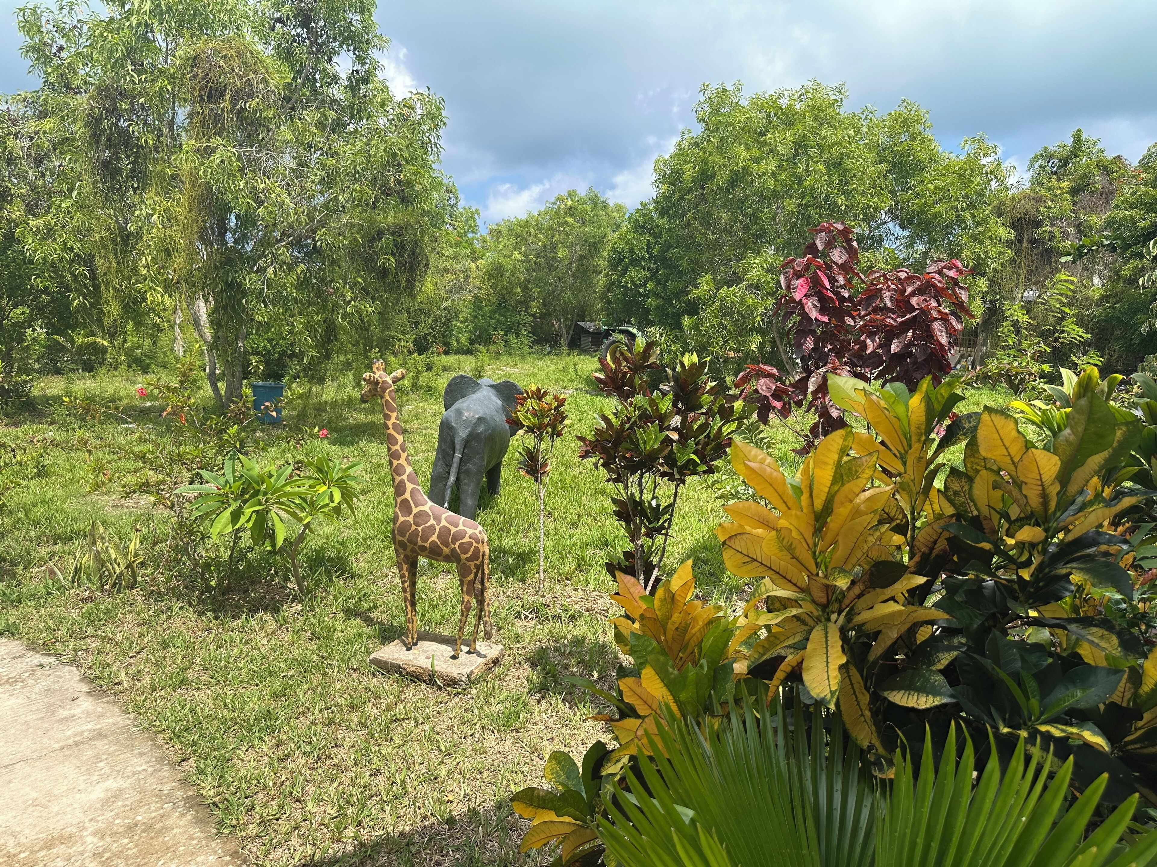 Un jardin orné d’une statue de girafe et d’un éléphant.