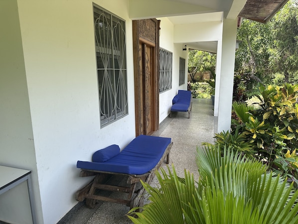 Un espacio al aire libre cubierto con dos sillones azules, un banco de madera y una mesita.