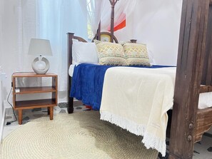 Un dormitorio con cama, mesita de noche, lámpara y un adorno en la pared.