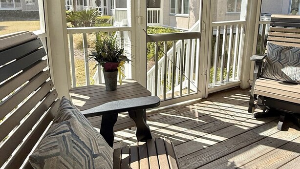 A covered outdoor seating area with a table and benches, overlooking a residential complex. - Newly Renovated First-Floor End-Unit Condo/Ocean Views/Beach Access/Free Parking (Isle of Palms)