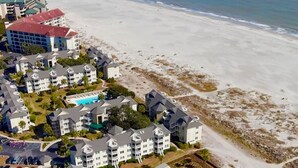 A coastal residential area with multiple two-story houses, a swimming pool, and a beach in the background. - Newly Renovated First-Floor End-Unit Condo/Ocean Views/Beach Access/Free Parking (Isle of Palms)