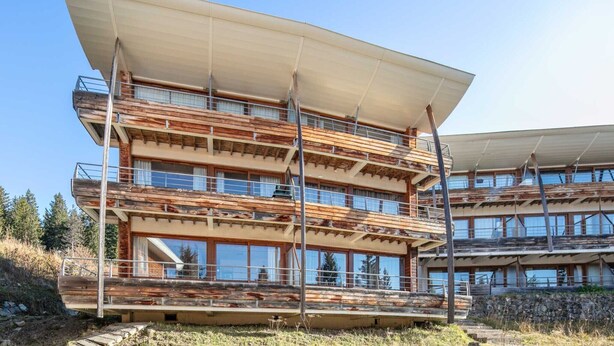 A multi-story building with a modern architectural design, featuring a flat roof and large windows. - Apt. in Chamrousse near supermarket (Chamrousse)