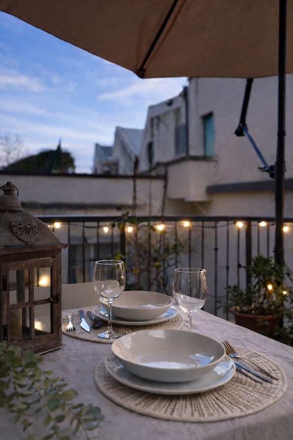 A table set for two with plates, glasses, and cutlery, under a canopy.