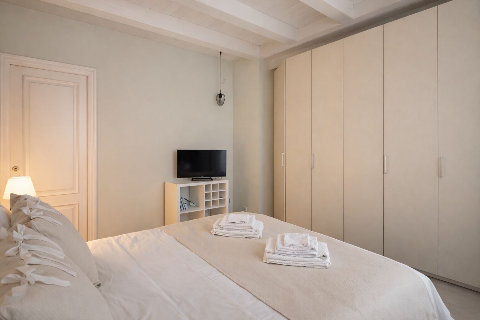Une chambre d’hôtel avec un lit, un téléviseur posé sur un meuble, une armoire et une lampe.