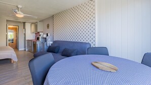 Ett modernt rum med ett runt bord, en soffa och en takfläkt.
