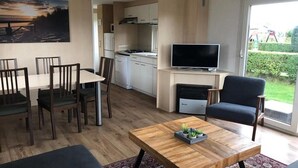 Un salon moderne comprenant un coin repas, une cuisine et un téléviseur.