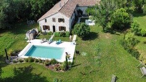 A stone house with a swimming pool, surrounded by a lush green lawn and trees. - Holiday home in Pardaillan with private pool (Pardaillan)