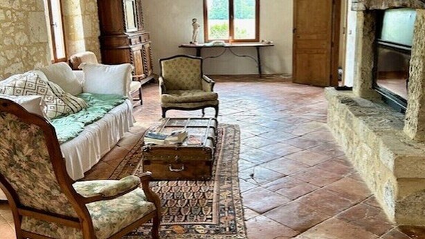 A spacious living room with a stone fireplace, a sofa, a chair, and a small table. - Holiday home in Pardaillan with private pool (Pardaillan)