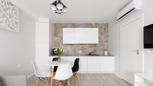 Een moderne keuken met witte kasten, een groot raam en een eethoek met een witte tafel en stoelen.