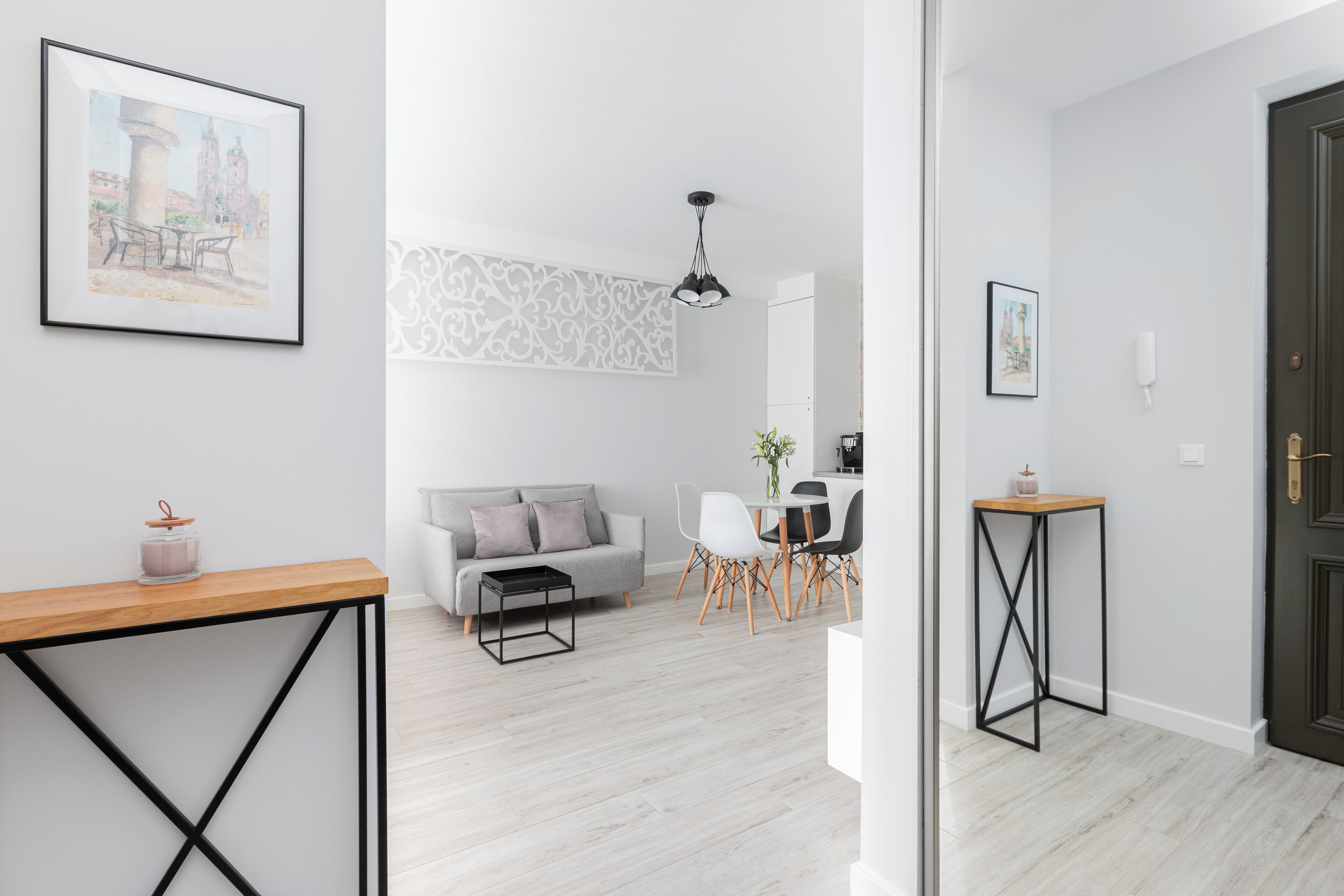 Una sala moderna con un sofá, una mesa de comedor y sillas. Hay una mesa de centro y una mesita con una vela.