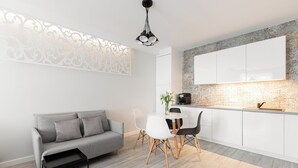 Een moderne keuken met witte kasten, een grijze bank en een eettafel met stoelen.