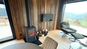 Ett modernt rum med en vedeldad kamin, en bekväm fåtölj och ett matbord.
