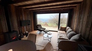 Ett mysigt rum med en soffa, stolar, ett litet bord, en tv och en öppen spis.