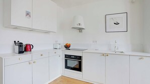 Una cocina moderna con armarios blancos, horno empotrado, hervidor y tostadora.