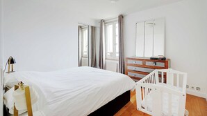 Un dormitorio con cama, cómoda, cuna y espejo.