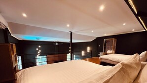Quarto moderno com uma cama grande, cómoda de madeira e ventoinha no teto.