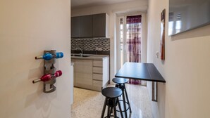 Una cocina compacta de diseño moderno, un área de comedor con una mesa y taburetes negros, y vistas a la habitación contigua.