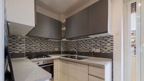 Una cocina moderna con armarios grises, salpicadero de azulejos, estufa a gas y un lavamanos.
