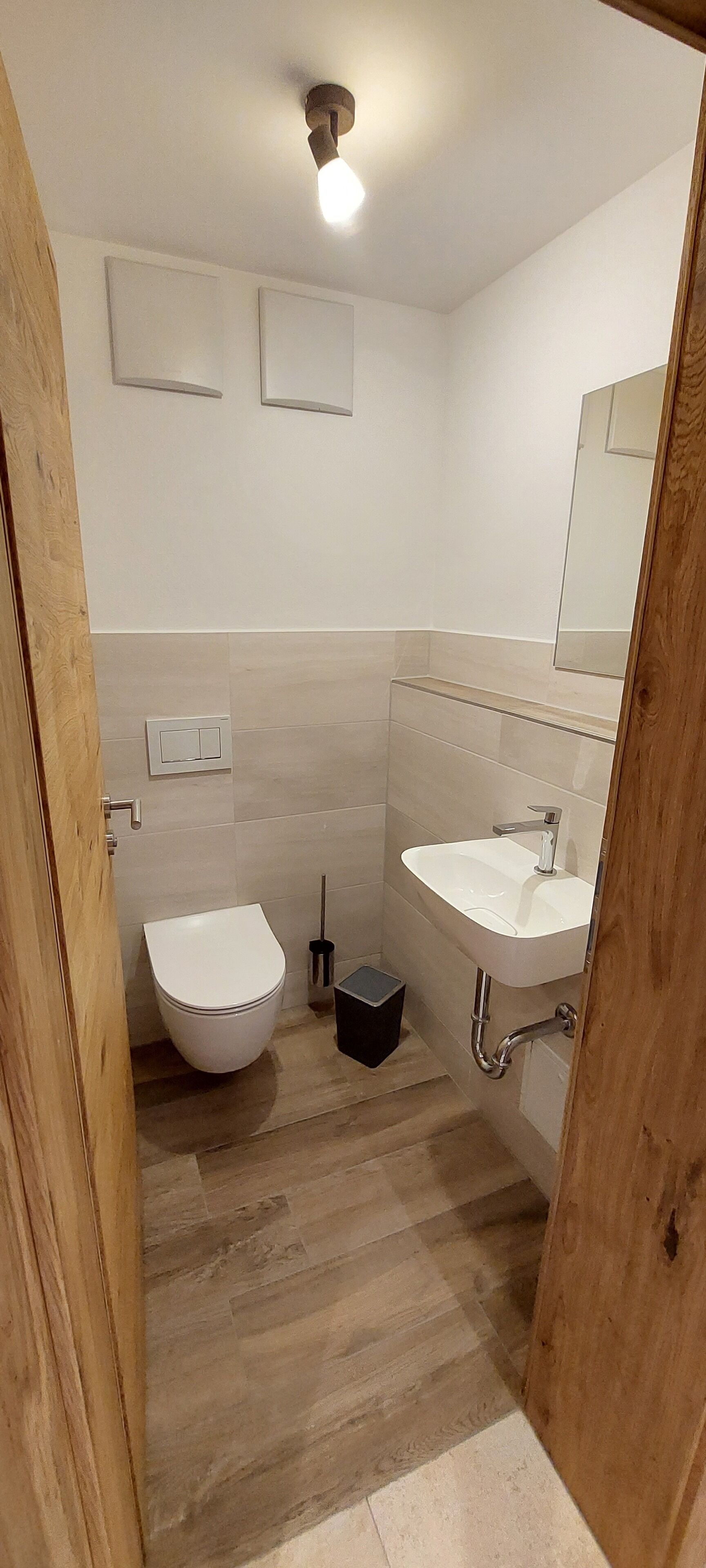 A small bathroom with a toilet, sink, and mirror.