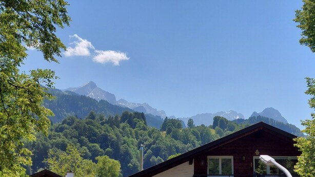 Una cabana de muntanya amb vistes a cims nevats i un bosc dens.