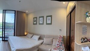 Une chambre d’hôtel comprenant un lit, un bureau, une chaise, une télévision, une fenêtre avec vue et une étagère avec des serviettes.